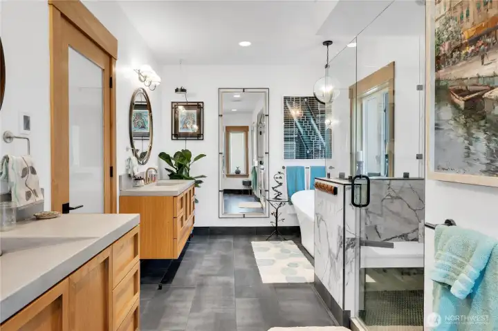 The bathroom features a tile-and-glass shower, a soaking tub, custom floating white oak cabinets with concrete vanity tops and integrated sinks, durable materials with functional design.