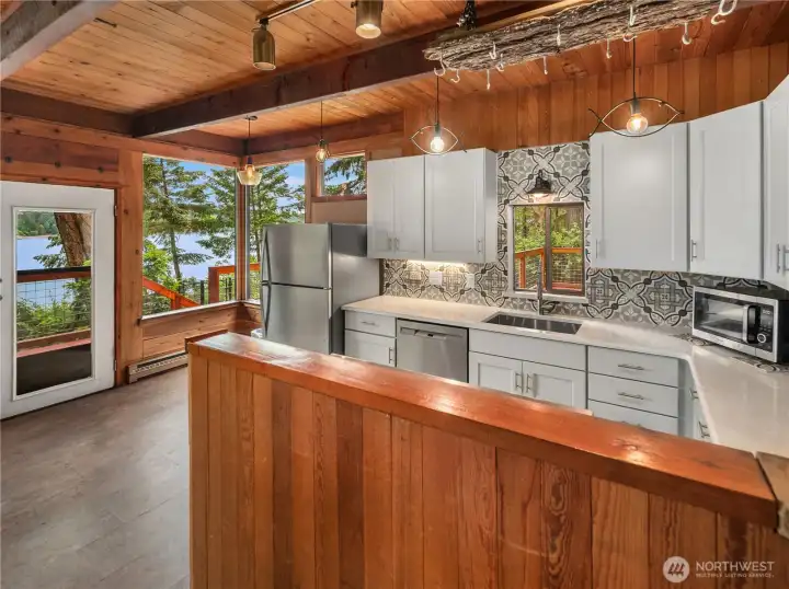 Updated open-concept kitchen showcasing crisp white cabinetry and stainless steel appliances.