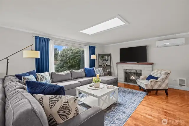 Living room with skylight, offers a wonderful gathering place. Wood burning fireplace, mini split, and wall heaters.