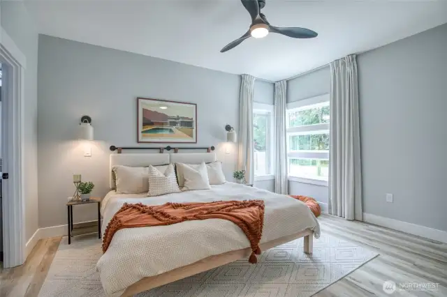 Primary suite with ceiling fan, wall sconce lighting, custom drapes