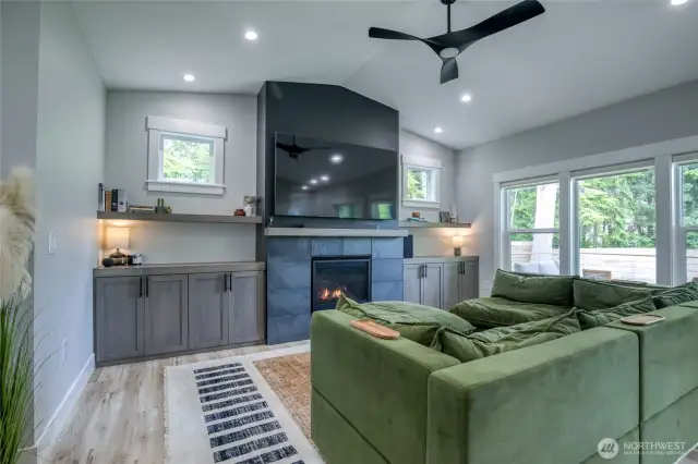 Open floor plan. Built-in cabinets and shelves, stacked stone propane fireplace, modern ceiling fan,