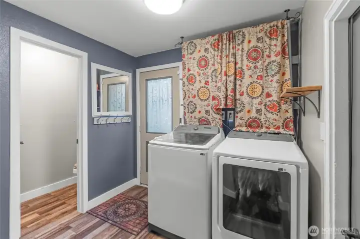 MAIN FLOOR | This bright space is the laundry room with a half-bath to the left and a door to the garage to the right. The door straight ahead leads to the back yard.