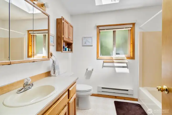 Upstairs Full bath, skylight, vanity and storage with clean, functional layout.