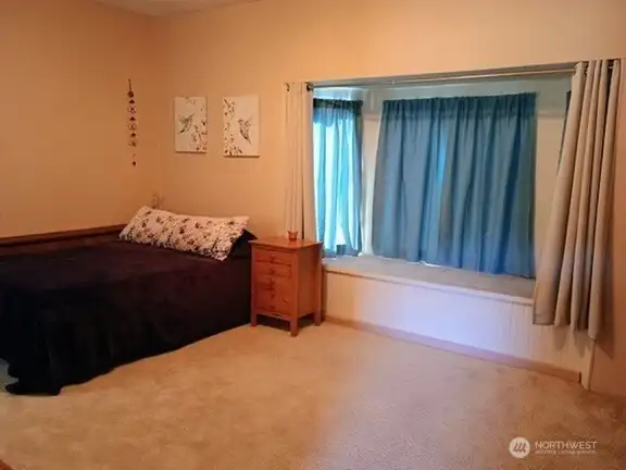 Spacious bedroom with bay window off living room of potential rental unit.