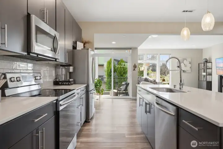 Cooking is a dream in this beautifully appointed kitchen, equipped w/ stainless steel appliances, quartz counters, full tile backsplash & abundant storage in sleek custom cabinetry.