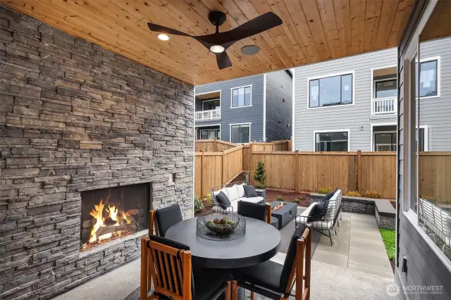 Covered outdoor luxury living area off of kitchen features gas fireplace & rich stone detailing