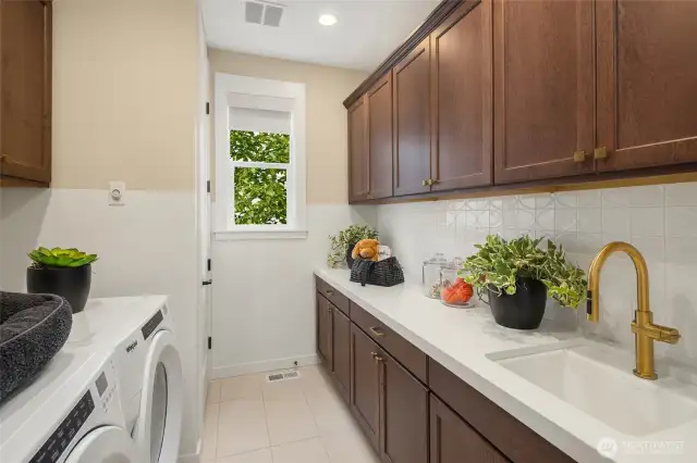 Laundry room conveniently located on upper floor includes expansive cabinetry for tons of storage, slab countertop & sink, Whirlpool front load washer & dryer AND utility closet