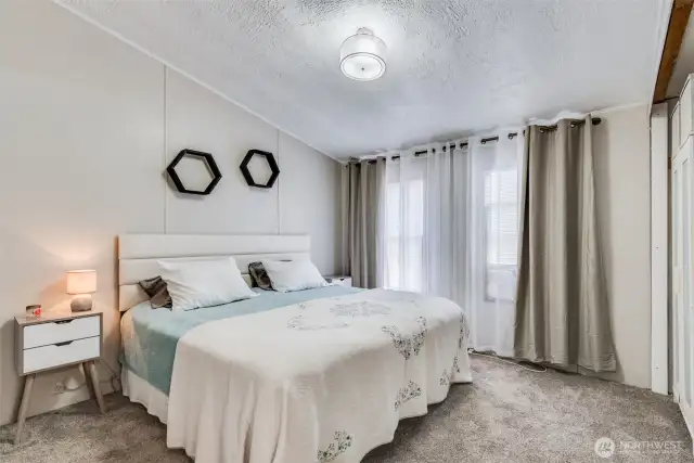Serene primary bedroom with vaulted ceiling, plush carpet, soft lighting, and dual windows for natural light.