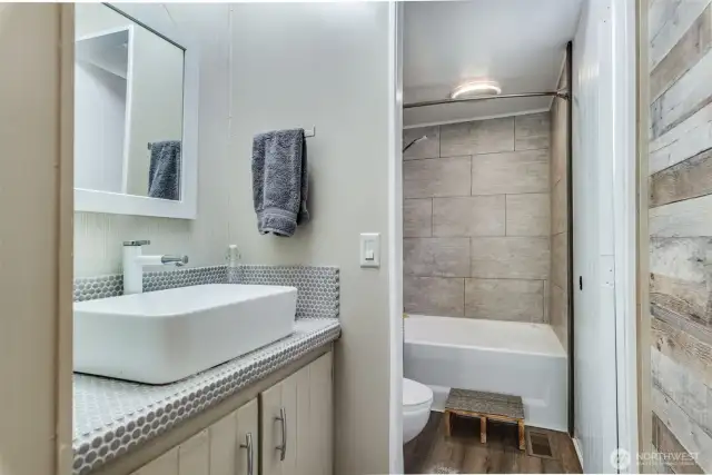 Primary bathroom includes a modern tiled vanity top w/new bowl sink and updated lighting & mirror.