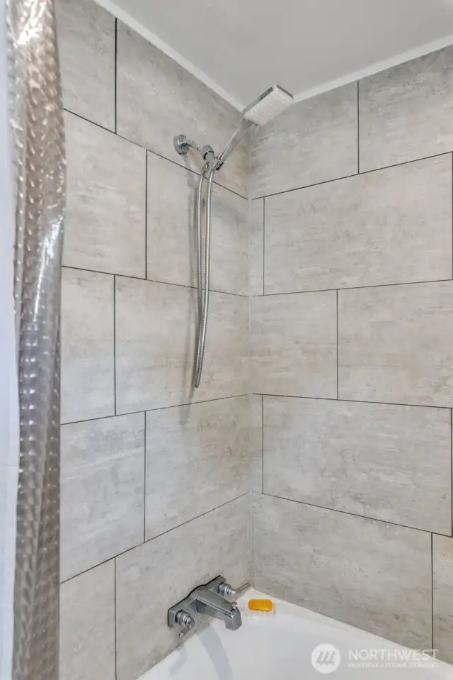 Beautiful, newly renovated tiled shower/tub combo offers both comfort and style.