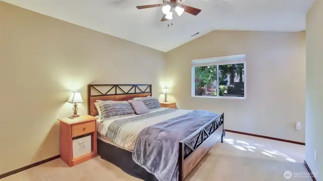 The primary bedroom is spacious with a vaulted ceiling and a ceiling fan.