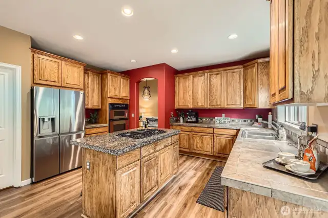 Spacious kitchen with abundant cabinetry, stainless appliances, and a center island with cooktop.