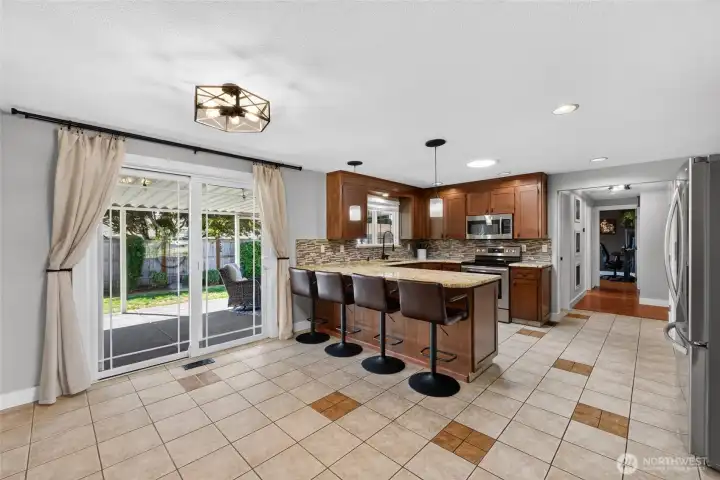 The updated kitchen features tile flooring, a roomy breakfast bar and a casual dining space overlooking the large covered patio & lush landscape