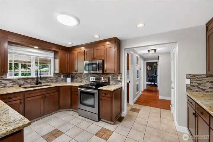 Featuring warm wood cabinetry (some with slide-out shelving) slab granite countertops and a glass tile backsplash, the kitchen is a gorgeous space for crafting wonderful meals