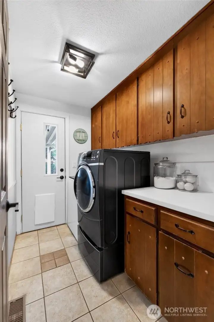 The laundry with access to the back yard has tile flooring, tons of storage, a folding counter, new board & batten wall and the washer & dryer are included.