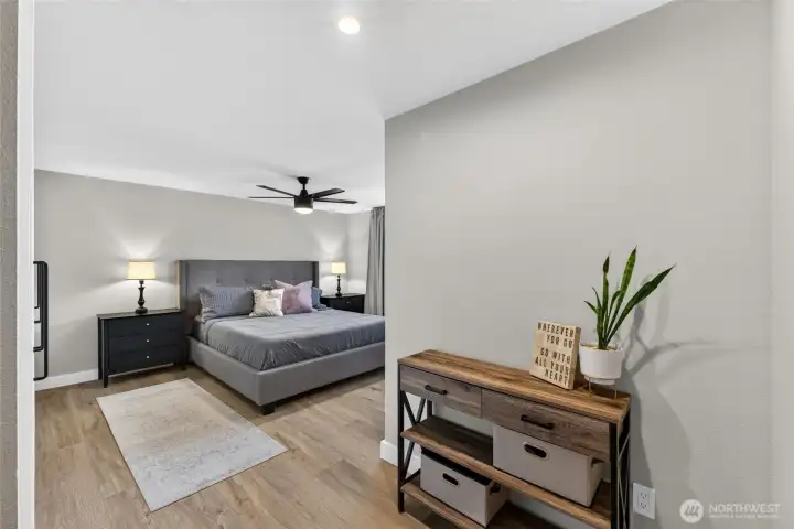 The spacious primary suite has new wide plank French oak Luxury Vinyl Plank flooring  and a decorative ceiling fan light