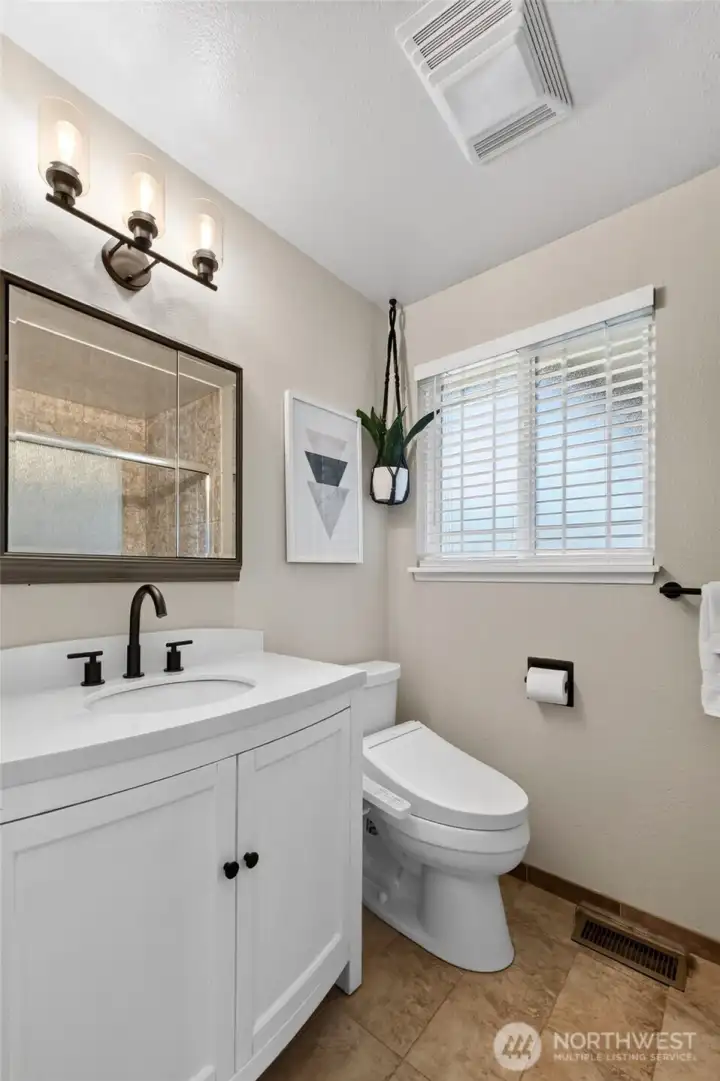The refurbished primary bath offers tile flooring & a nice vanity with engineered countertop