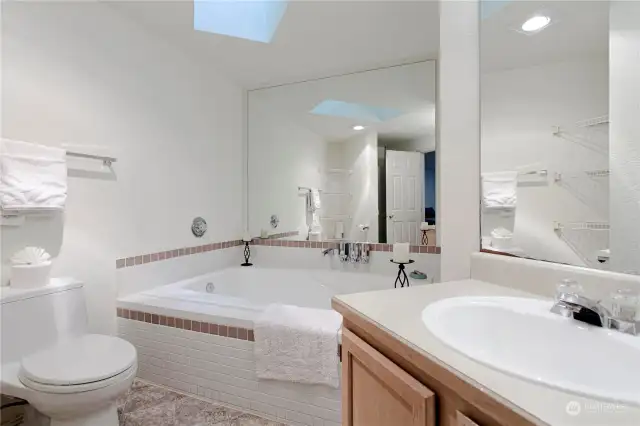 Gorgeous primary suite bathroom - soaking tub, skylight, and a separate shower.