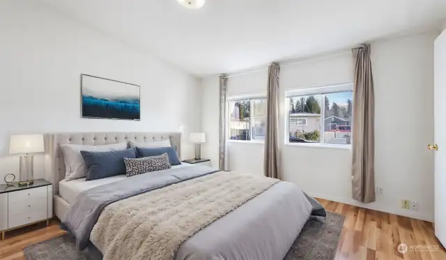 Primary suite with vaulted ceiling and solid engineered hardwood floors (virtually staged).