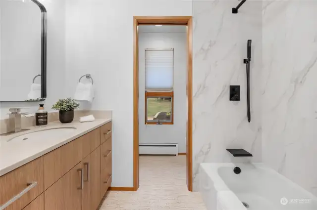 Main bathroom with new vanity, quartz counters, mirror, hardware, lighting and tile tub surround.