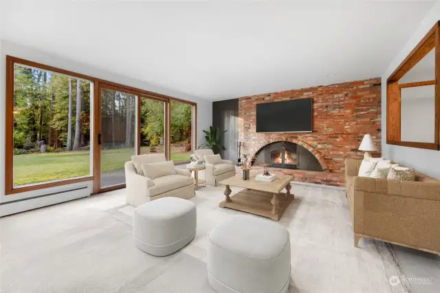 Spacious family room with handsome brick fireplace, new carpet, and lovely view to the back yard. (digitally staged)