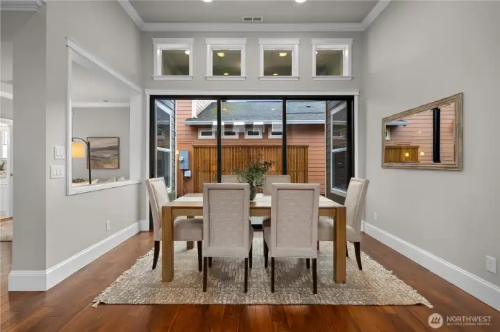 The dining area is bathed in natural light and the 3-panel sliding glass door is striking.