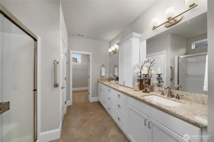 Primary bathroom offers gorgeous Quartz counters, two undermount sinks, upgraded fixtures and tile flooring.