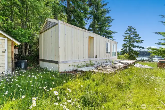 Existing Park Model home, with waterfront deck. Structure to the left is a wood shed.