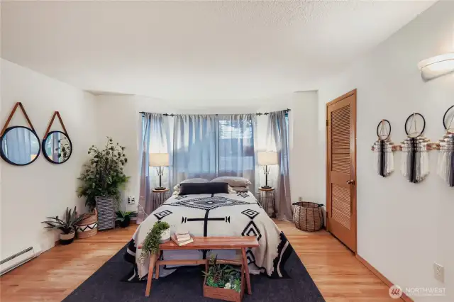 Generously sized primary bedroom featuring hardwood floors, a bay window seating area, and abundant natural light.