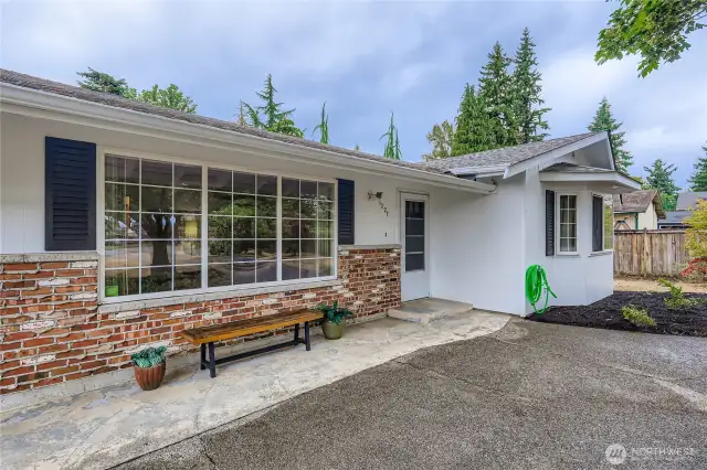 Charming front entry with brick accents and a wide picture window, offering a warm welcome