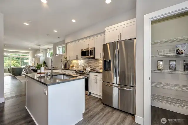 Wide plank luxury laminate flooring throughout main floor, full height tile back splash, slab quartz counters, island, stainless appliances and walk-in pantry make this the ideal chef's kitchen.
