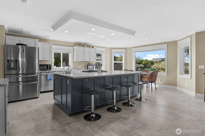 Spacious, open concept kitchen and dining look out to living room with fireplace