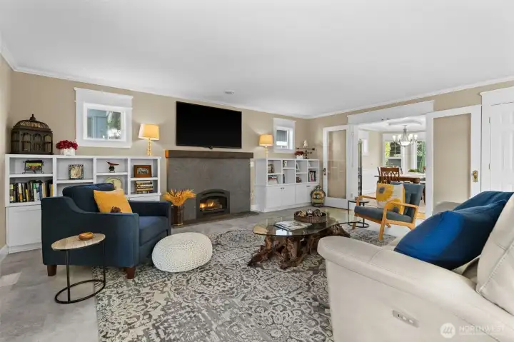 Living room off kitchen with built-ins, a cozy gas fireplace and new flooring