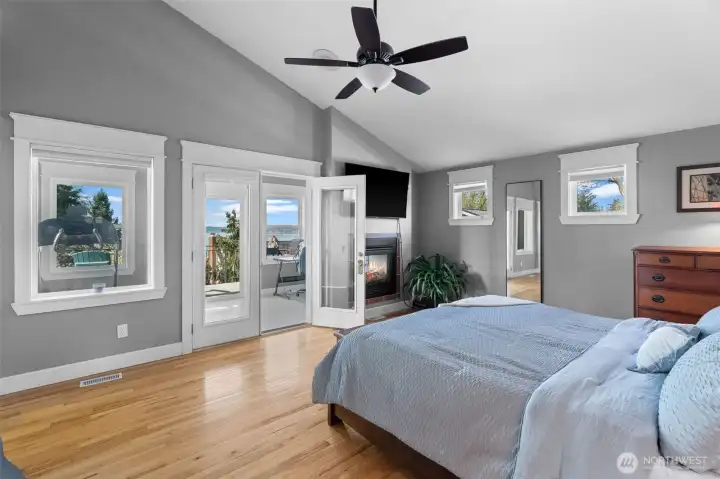 Primary bedroom with vaulted ceilings, gas fireplace, luxury bath and bonus sunroom with deck with water views