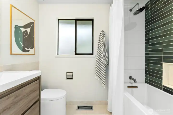 The fully renovated primary bathroom with a tub/shower combo, a new vanity, water-wise toilet, marble flooring and on-point subway tiling.