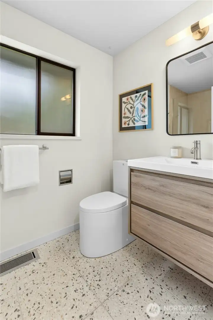 The main hallway bathroom with fun, colorful Terrazzo flooring, a new vanity and a water-wise toilet.