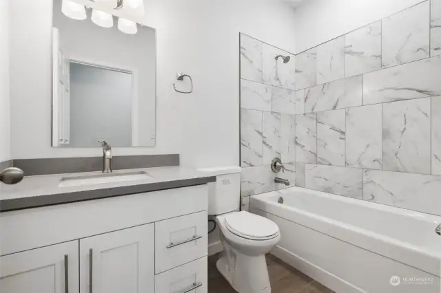 Guest Bathroom with custom tile work, laminate floors and quartz countertop.