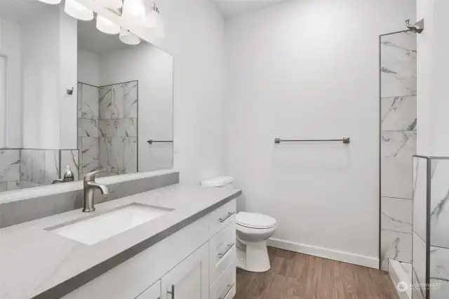 The primary bathroom, large vanity, quartz countertop, bathtub, shower and custom tile work.