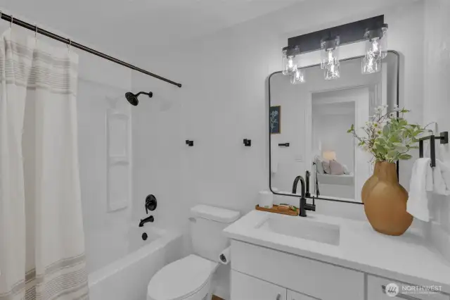 The full bathroom features modern black fixtures, white cabinetry, and a tub/shower combo with contemporary finishes throughout.
