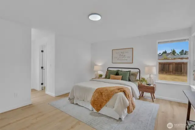 The primary bedroom features a large window overlooking the backyard and includes an en-suite bathroom accessible through the adjacent doorway.