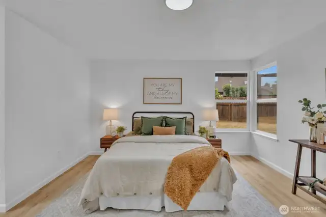 Dual windows flood the bedroom with natural light while offering peaceful views of the private fenced yard.