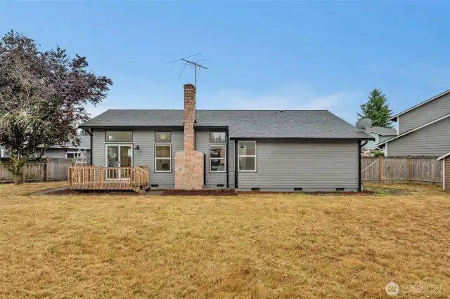 The home's rear elevation showcases the deck for outdoor dining and the generous yard space beyond.