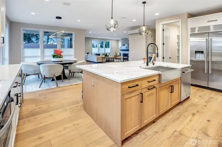 The oversized center island is the true hub of the home, offering generous prep space, seating, and seamless connection to the dining and great room. Warm wood tones, sleek black hardware, and modern globe pendants add layered texture and sophistication, while the open layout keeps the kitchen at the heart of daily living and entertaining.