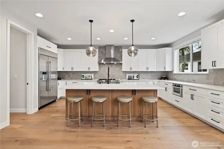 A chef-inspired kitchen anchored by a premium JennAir refrigerator and a 48-inch professional gas range. Expansive quartz surfaces, a deep stainless farmhouse sink, and curated pendant lighting combine to create a workspace that is both functional and beautifully designed. The walk-in pantry just beyond the refrigerator offers exceptional storage and organization.