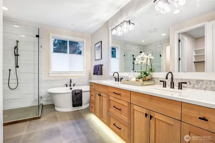 The serene primary bath showcases a relaxing freestanding soaking tub, an expansive glass-enclosed shower with designer tile, and heated tile floors. Thoughtful finishes and generous counter space offer both luxury and everyday functionality.