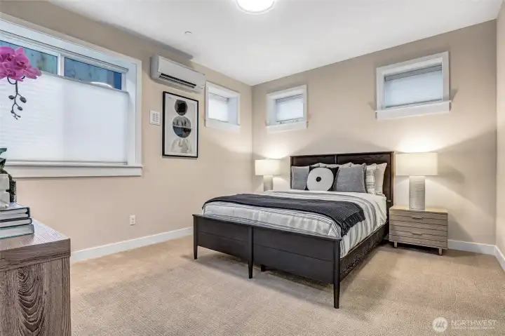 Bright and private lower-level bedroom featuring soft natural light from three elevatred windows, plush carpeting, and a neutral palette that complements any style. A perfect guest suite, teen retreat, or exercise room.