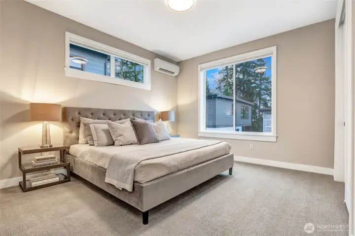 Spacious secondary bedroom with large windows, soft neutral palette, and ample room for full-size furniture.