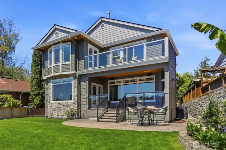 Stunning view of the home from the water. An entertainers dream home! Covered deck off of the kitchen and concrete stamped patio.