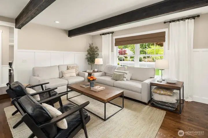 Another angle of the sun-drenched living room showcases the generous proportions and warm hardwood floors, with garden views through the large windows creating a seamless connection to the lush private backyard beyond.