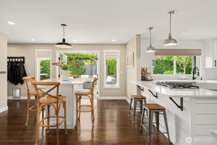 The well-appointed kitchen dazzles with all-new appliances, ample white cabinetry, and a generous island, while the bright eating nook beyond is wrapped in windows that pour in natural light and frame the lush backyard.